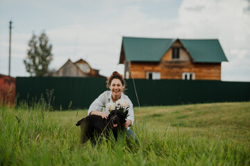 Female with pet dog and flowers relaxing in rustic backyard garden on summer day. Woman enjoying leisure, nature and eco-friendly lifestyle outdoors