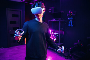 Single player game. Young man is in virtual reality glasses indoors