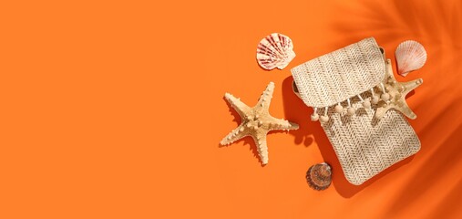 Composition with stylish beach bag and sea shells on orange background with space for text