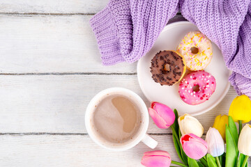 Small sugar glazed donuts with coffee latte cup, tulip flowers, sweater and tulip flowers