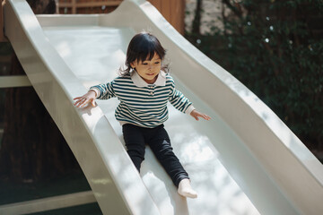 toddler baby girl sliding and playing at playground