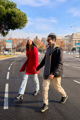 Happy couple holding hands and walking down the street in madrid