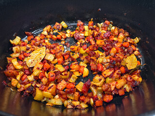 Golden fried vegetables with bay leaf in a black pot