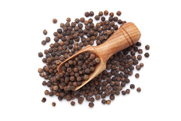 A wooden scoop filled with organic Black pepper (Piper nigrum) is placed on a heap of whole black pepper, isolated on a white background.