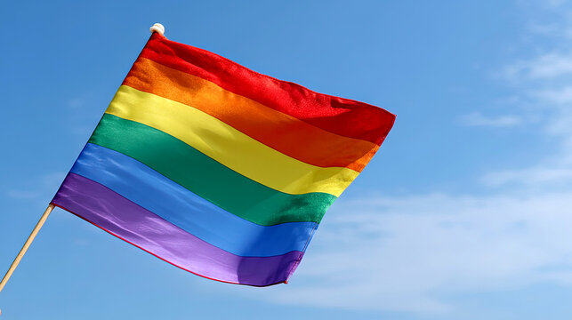 Person holding transgender pride flag against clear blue sky, symbolizing gender identity, inclusivity, and LGBTQ+ support