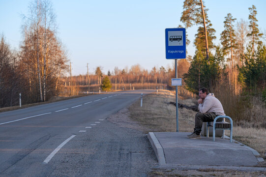 Waiting at a bus stop on a quiet road in early morning light