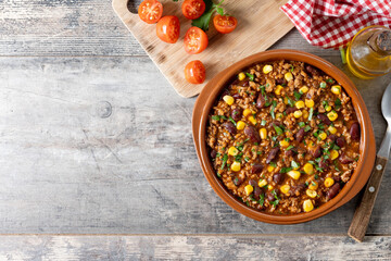 Traditional Mexican Chili con carne. Minced meat and vegetables stew in tomato sauce on wooden table