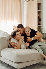 Happy family relaxing and cuddling on sofa at home