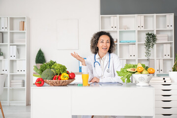 Mature female nutritionist sitting at table in office
