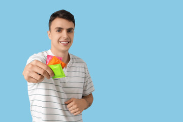 Young man showing condoms on blue background