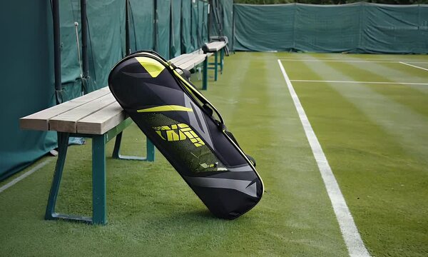 Tennis racket bag resting on tennis court bench.