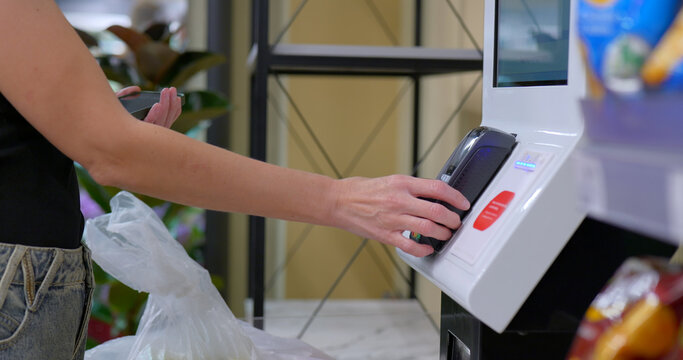 Customer makes contactless payment with card at grocery checkout