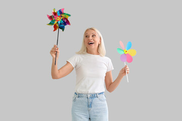 Mature woman with toy windmills on light background