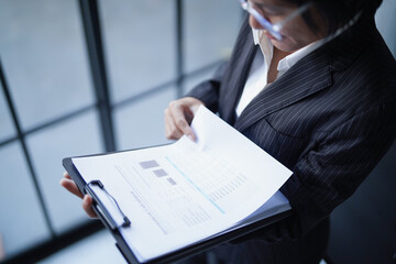 Asian businesswoman in suit standing reading documents