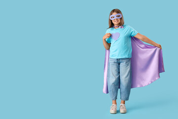 Teenage girl dressed as superhero on blue background