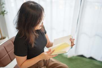 Asian woman reading a book in living room