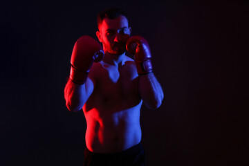 Man in boxing gloves on black background in neon lights