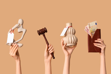 Female hands with auction gavel, wallet and antique items on beige background