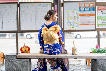 It's a rainy summer day. bus stop. A Japanese woman in a teenager wearing a blue kimono folded and...