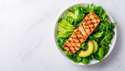 Grilled salmon fillet served on fresh green salad with avocado slices.