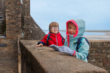 Siblings kids smiling at a seaside fortress Mont Saint Michel