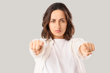 Young woman pointing at viewer on light background, closeup. Rules concept