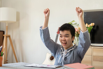 Celebration and Achievement. A teenage girl with Down syndrome raises her arms in joy after...
