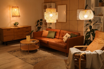 Interior of stylish living room with brown sofa, coffee table and glowing lamps at evening