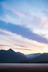 Twilight over Vatnajökull glacier in Iceland, with snow-covered peaks, pastel sky, rising crescent moon, and mist-covered plains evoking stillness and grandeur.