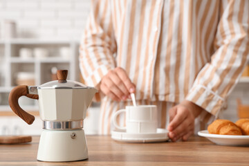 Young woman in pajamas making breakfast at home, focus on geyser coffee maker