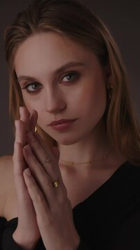 Beautiful girl with gold jewelry and loose hair in black clothes posing on a dark background. Beauty face and hair. Video 4k