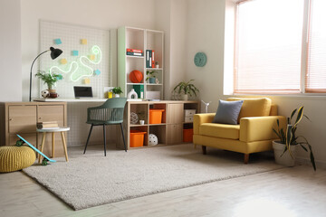 Interior of teenager's room with workplace, shelf unit and armchair