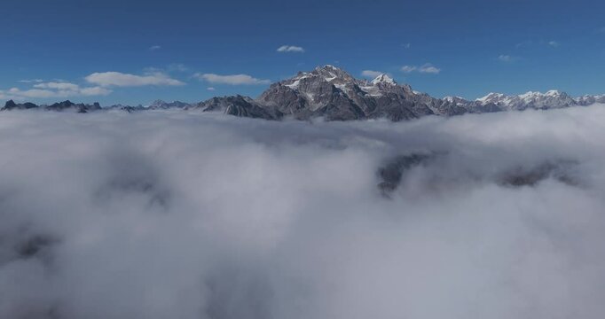 Aerial view approaching a rocky mountain in middle of low hanging clouds in Nepal