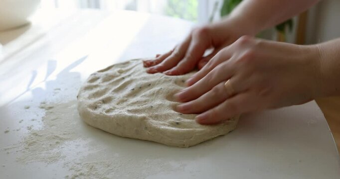 Close-up footage of hands kneading fresh bread dough on a floured surface. Perfect for themes related to baking, home cooking, artisan food, and slow living.