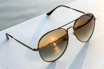 Stylish Round Sunglasses with Gradient Lenses on White Surface with reflected senery