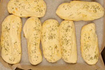 A close-up shows several golden-brown bread rolls seasoned with garlic and oregano, suggesting a flavorful and aromatic baked good