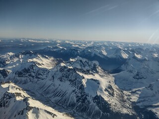 Fototapeta premium Aerial view of snow-covered mountains under a clear sky.
