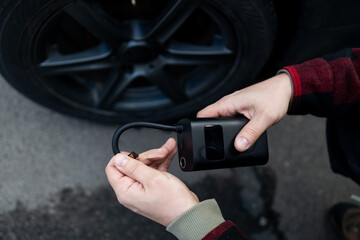 man driver hand inflating tires of vehicle, removing tire valve nitrogen cap for checking air pressure and filling air on car wheel at gas station. self service, maintenance and safety. High quality