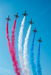 Jet planes performing aerial show with red white and blue smoke trails in clear sky for bastille day in france