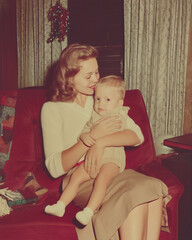 stylish mother holding child in lounge at christmas, vintage color photo, old and faded 1960s mom