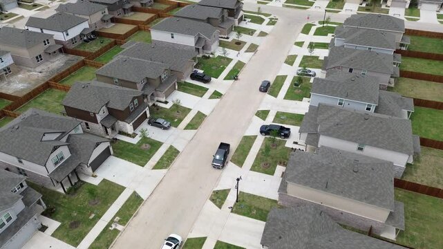 Large residential street in new construction neighborhood row of upscale two-story suburban completed houses and incomplete home buildings in Princeton, Collin County, TX, wooden fence, flyover