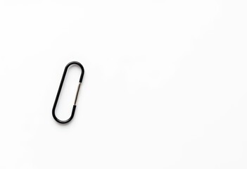 Obraz premium A single black paperclip rests on a pristine white background, backdrop, photography