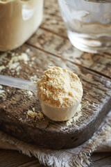 Whey protein powder in a transparent measuring spoon