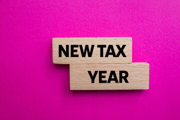 New tax year message written on wooden blocks on pink background. Conceptual new tax year symbol. Copy space.