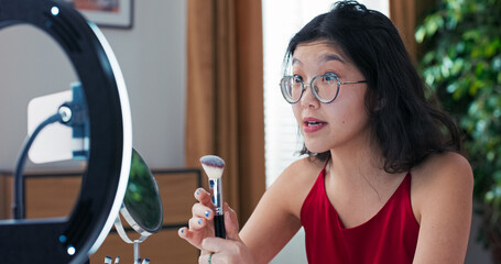 Stylish woman records short-form beauty videos, explaining differences in makeup brushes. Her...