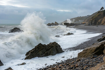 Powerful Waves Crashing Against Coastal Rocks on a Cloudy Day