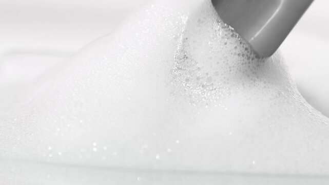 Cosmetic soap foam with brush for applying makeup close-up, front view.