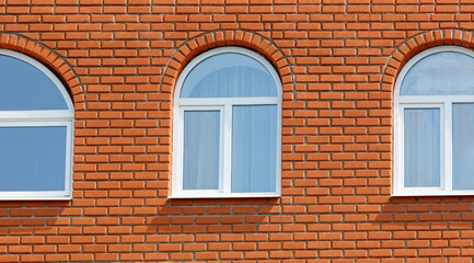 Fototapeta premium Three windows on a brick wall with a white trim