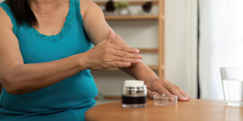Beauty and Wellness. An elderly woman applying skincare cream to her arm, focusing on self-care.