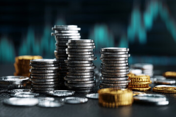 Close-up of stacked silver and gold coins against a blurred teal background, showcasing financial growth and wealth accumulation, ideal for business or finance concepts